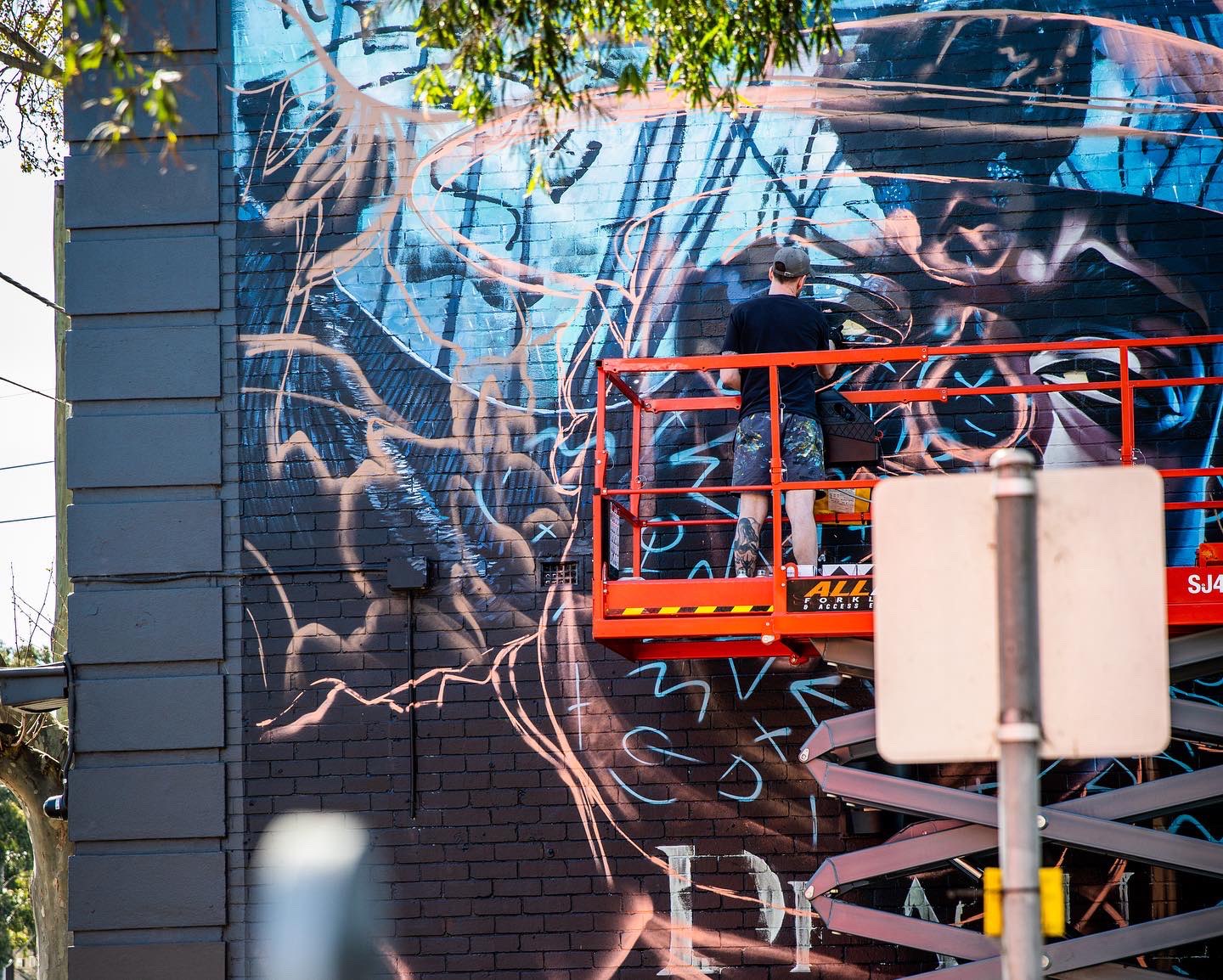 Artist painting mural from scissor lift