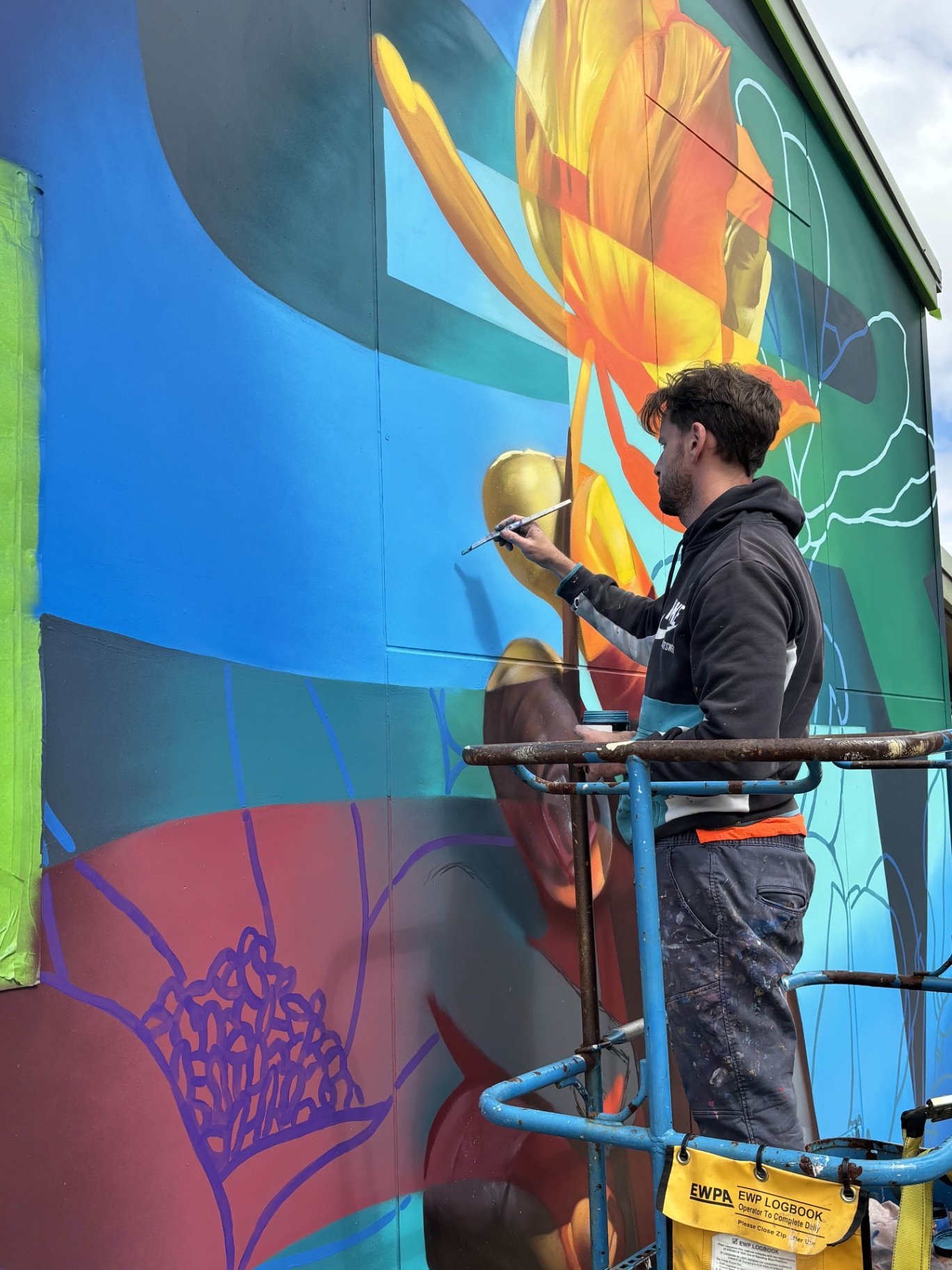 Artist working on the flower motif from a scissor lift