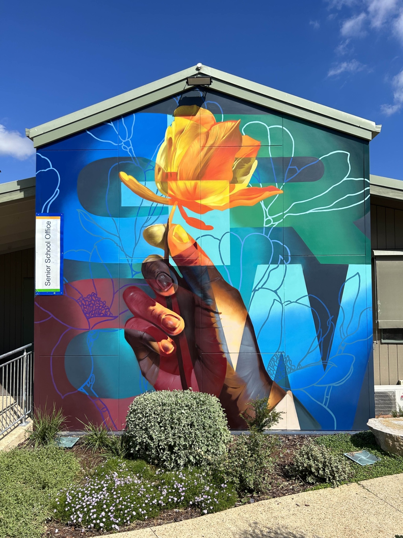 Completed GROW mural with hand and flower on the Senior School Office wall