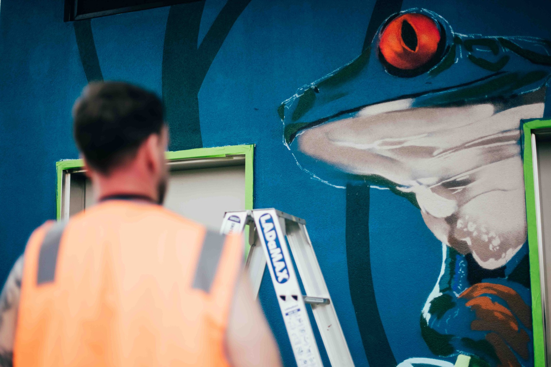 Artist sketching the frog motif on the blue base coat
