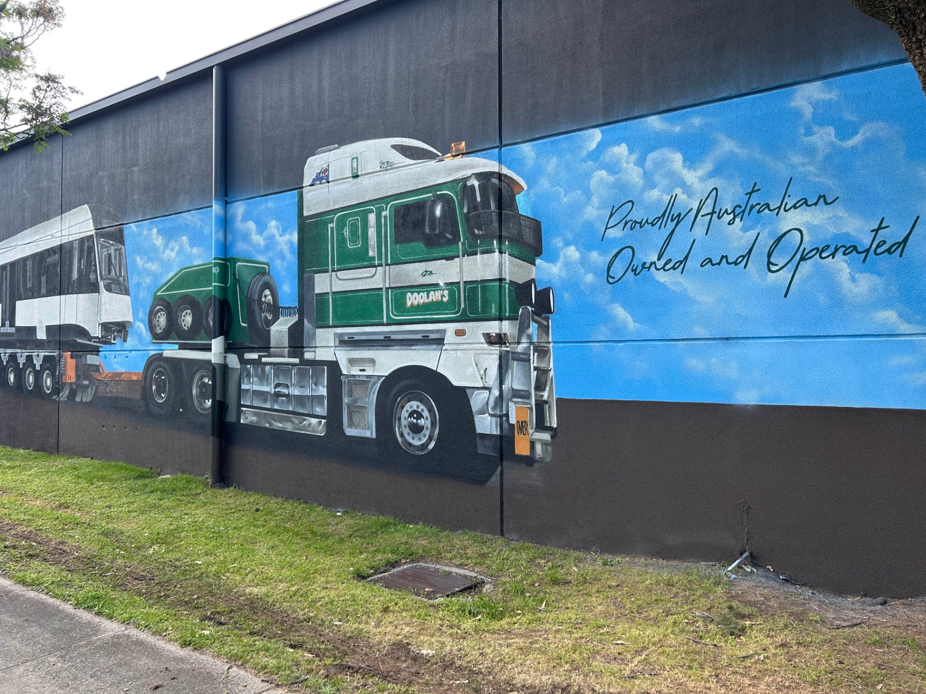 Doolans green cab-over truck mural with 'Proudly Australian Owned and Operated' script