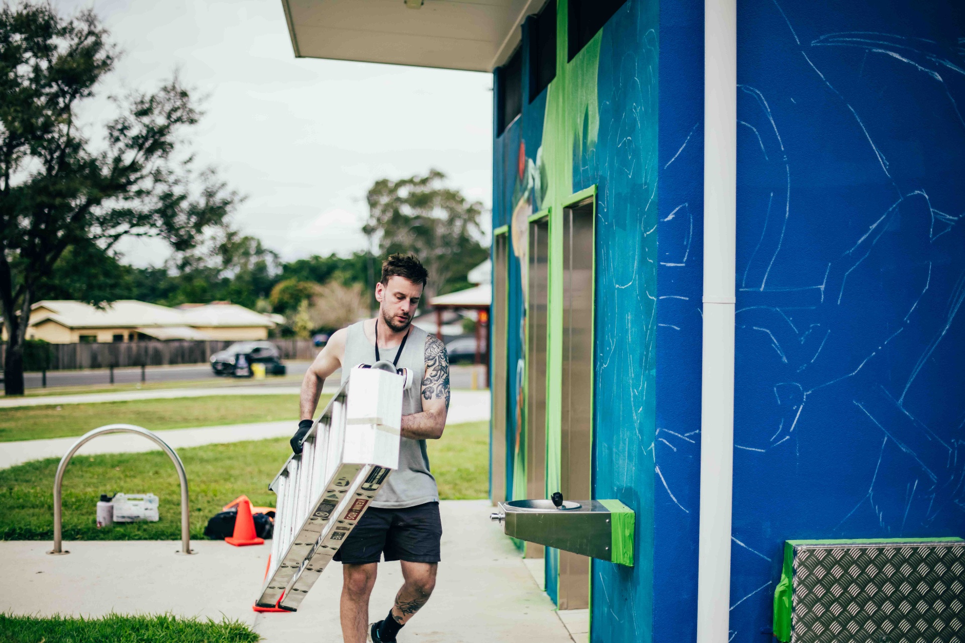 Artist carrying a ladder alongside the mural site