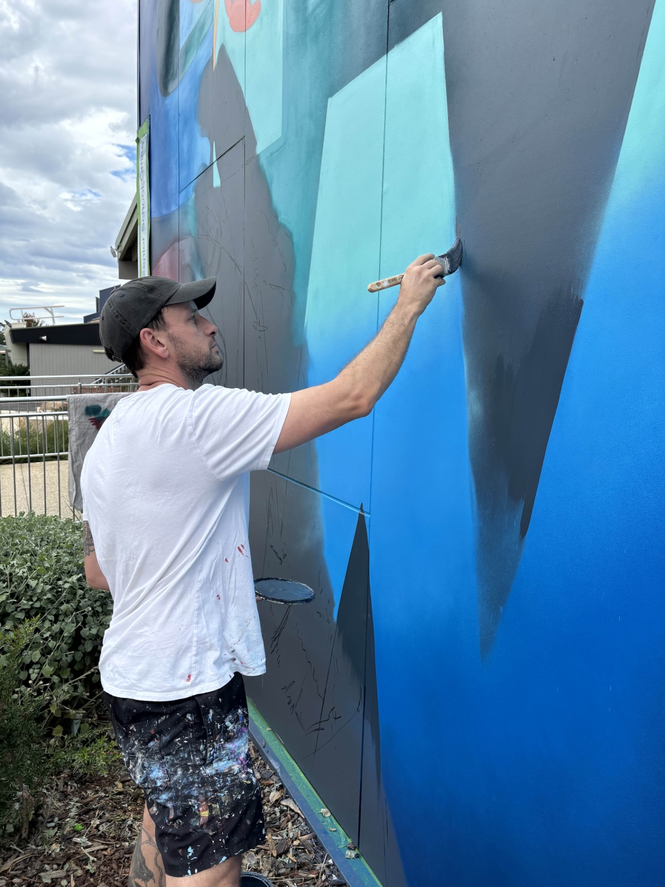 Artist brushing in base colours during the GROW mural build