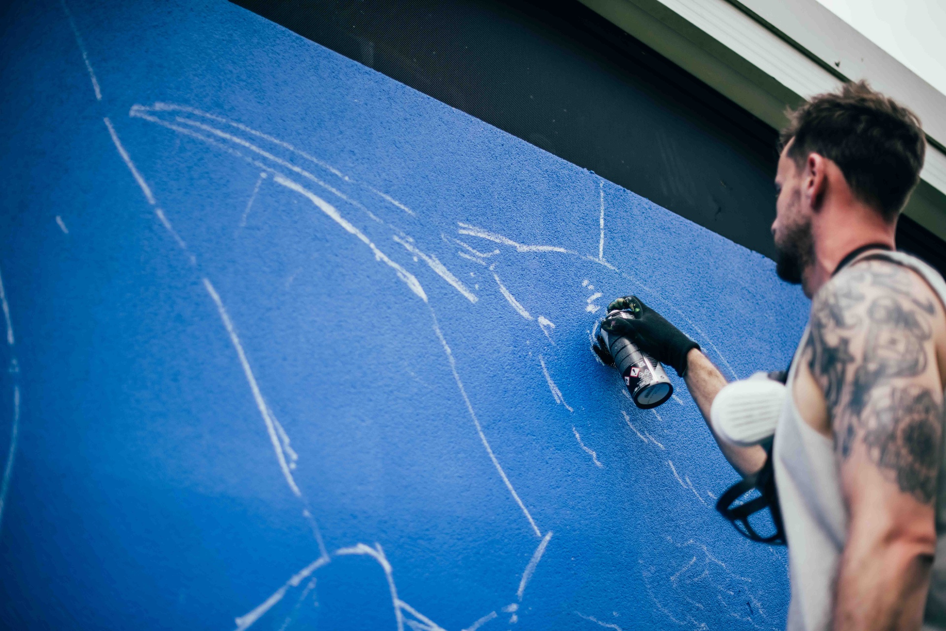 Sketching linework over the blue base of the mural
