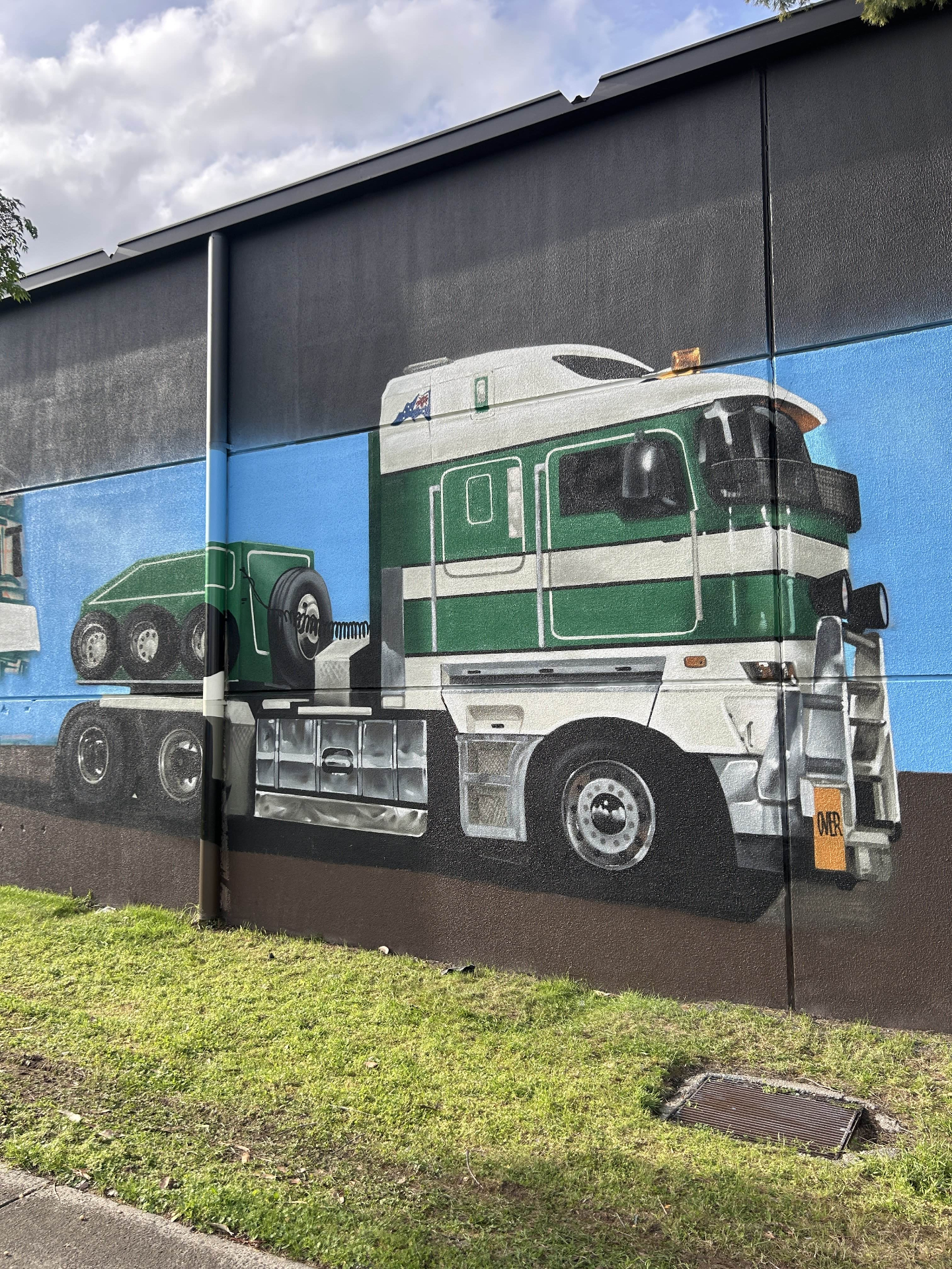 Green and white cab-over truck mural detail with blue sky backdrop